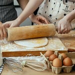women making dough on chopping board on table