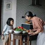 happy woman with little girl preparing healthy lunch