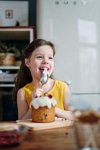 LIttle girl smiling and eating dessert