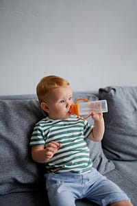 Child sitting on the couch and drinking water
