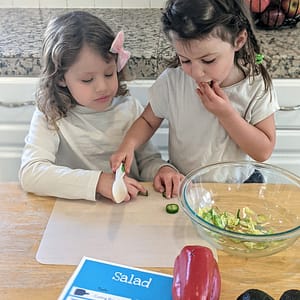 Two girls cutting vegetables for their salad