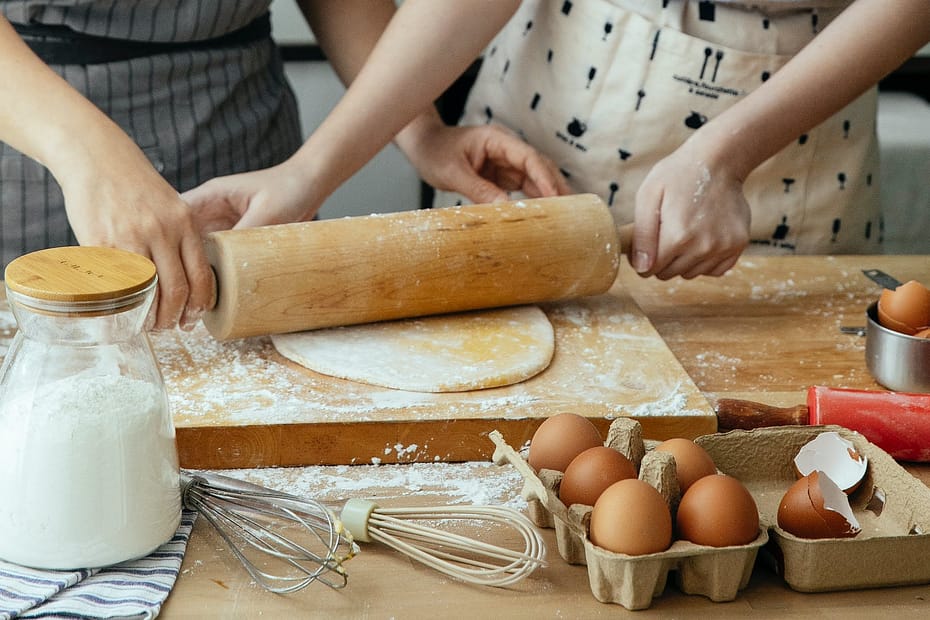 women making dough on chopping board on table
